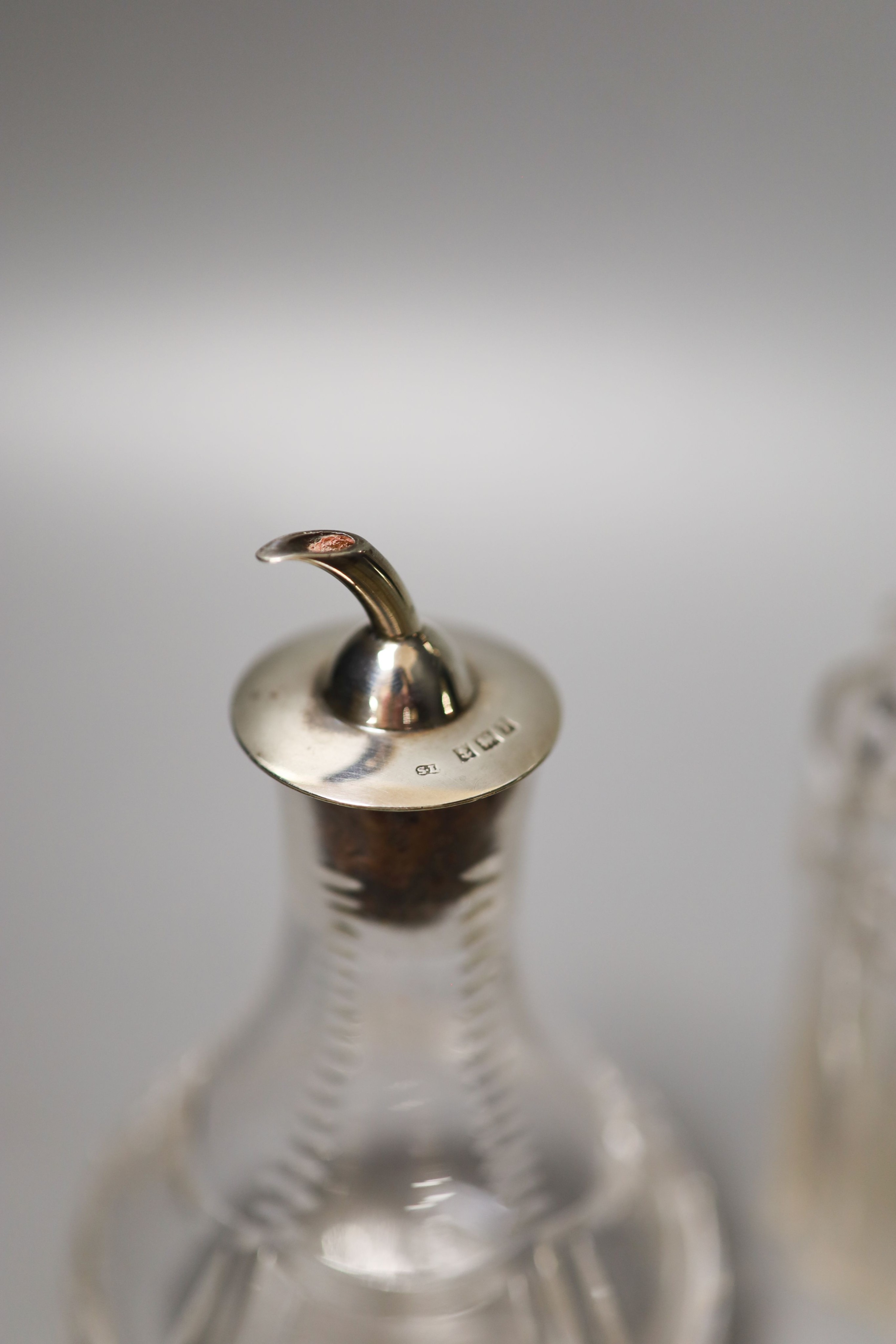 A pair of modern silver mounted glass butter dishes, a silver toastrack, three silver mounted glass bottles and three pairs of silver sugar tongs.